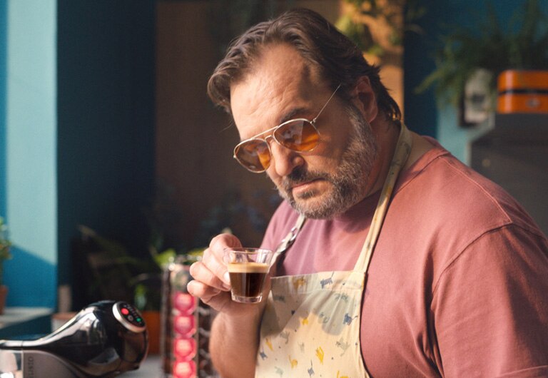 A man posing with the coffee he just made at home